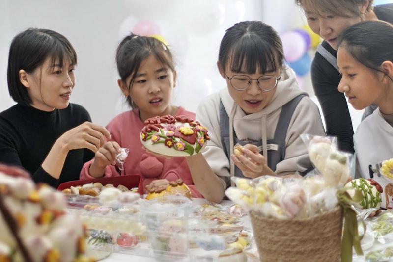 Tian Xiao (katikati) akibadilishana maoni na marafiki zake kuhusu Mianhua. (Picha na Li Xin/Xinhua)